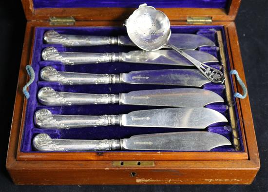 A cased set of fish eaters and a silver strainer.